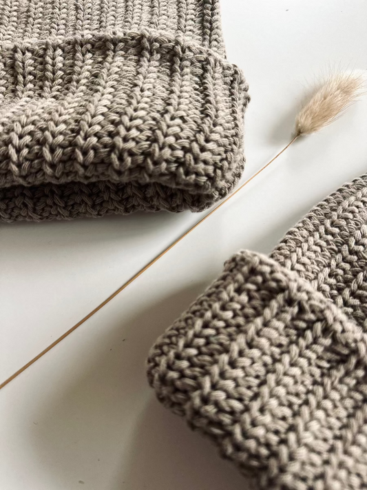 Two chunky knit beanie hats gray brown folded knitted items on a light wooden surface