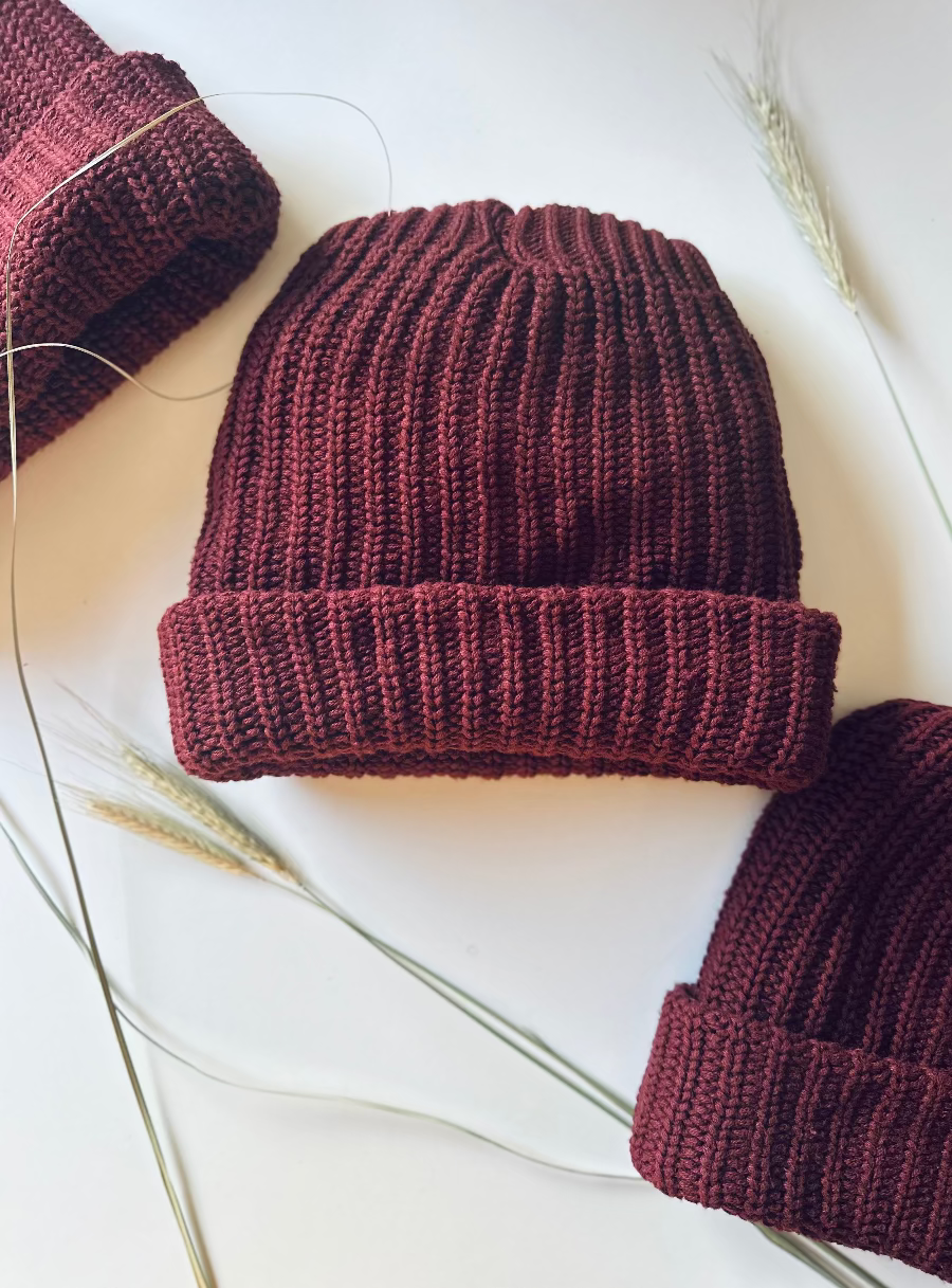 Chunky Knit burgundy beanie Socks on a white surface with dried plants.