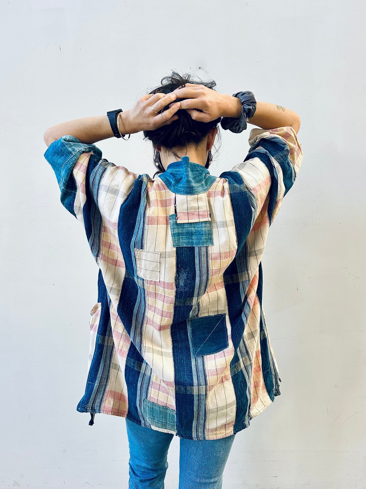 Person wearing a patchwork shirt with a plain background