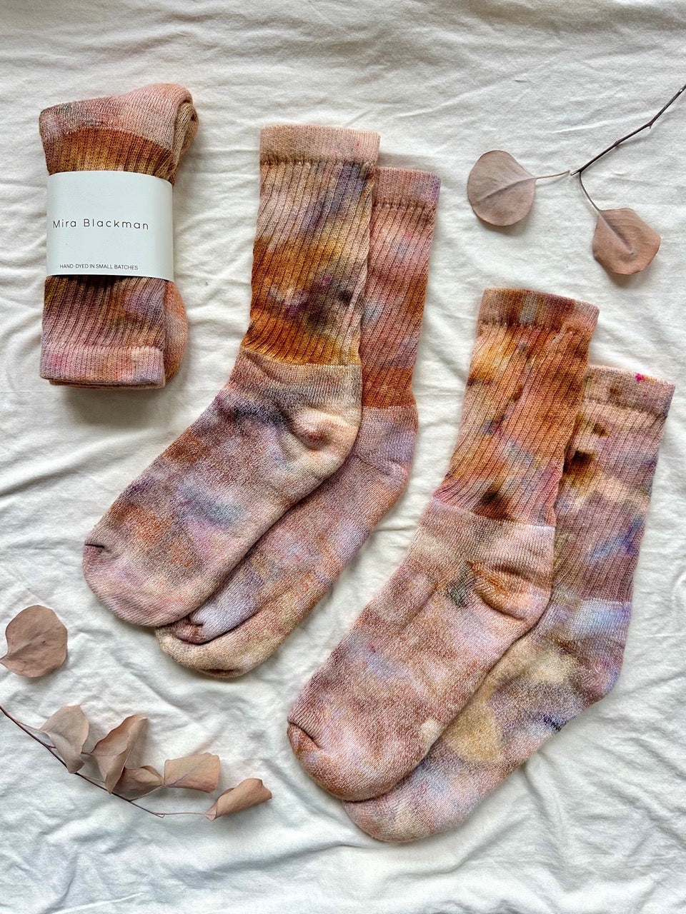 Pair of patterned socks on a textured surface with a brand label.