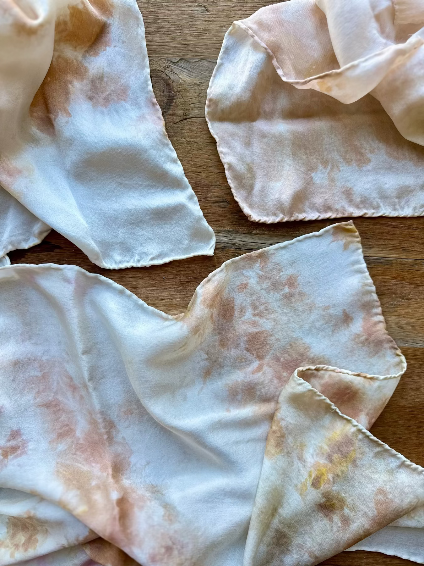 Softly draping hand dyed silk scarves on a wood table 